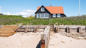 A coastal house with a red roof, white windows, and a flag. - 5 Person Holiday Home in Juelsminde (Juelsminde)
