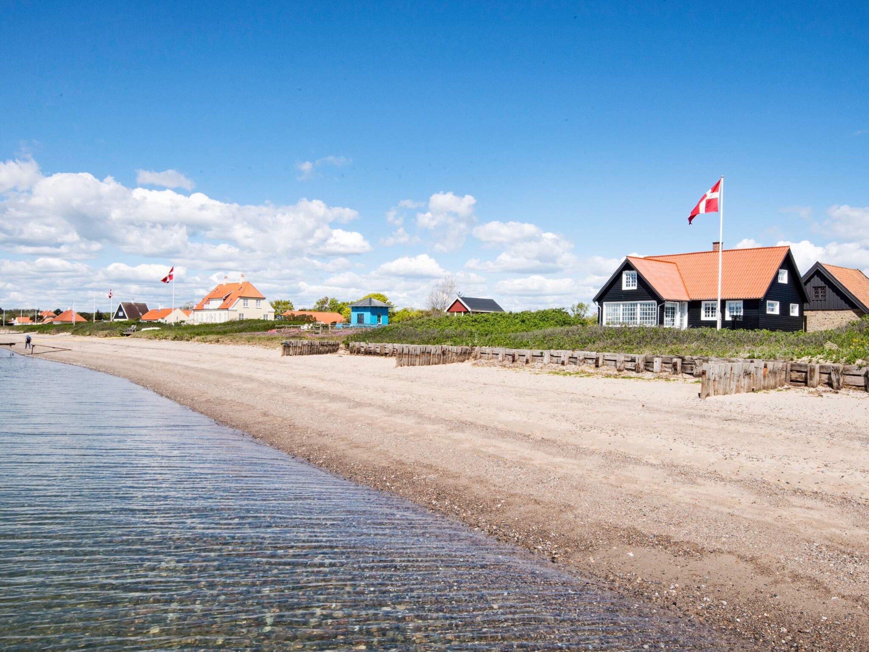 A coastal area with houses, a sandy beach, and a calm sea.