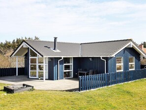 Una casa moderna con un amplio balcón, una chimenea y un patio cercado.