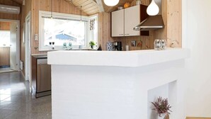 A modern kitchen with wooden walls, a white countertop, and pendant lights. - 4 Star Holiday Home in Thisted (Thisted)