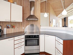 A modern kitchen with a stainless steel range hood, white cabinetry, and a curved countertop. - 4 Star Holiday Home in Thisted (Thisted)