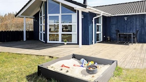 A modern house with a large glass door, a deck, and a sandpit. - 4 Star Holiday Home in Thisted (Thisted)