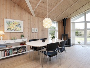 Un interior moderno con una mesa de comedor redonda, sillas negras, una estantería, un cuadro y una chimenea.