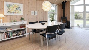 A dining area with a round table, black chairs, a white cabinet with books, and a painting on the wall. - 4 Star Holiday Home in Thisted (Thisted)