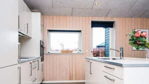 A modern kitchen with wooden panel walls, a window with a view, and a sink.