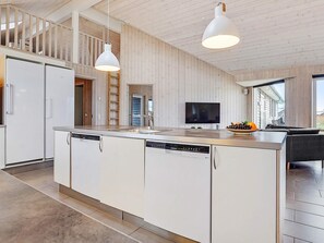 A modern kitchen with a central island, built-in dishwasher, and a large window.