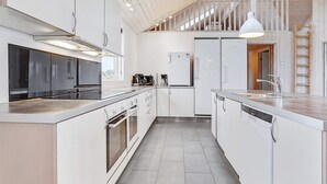 Een moderne keuken met witte kasten, roestvrijstalen apparatuur en een centraal keukenblok met een spoelbak.