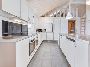 A modern kitchen with white cabinetry, stainless steel appliances, and a central island with a sink. - 5 Star Holiday Home in Sydals (Sydals)