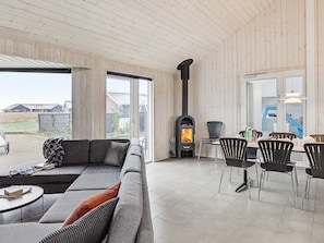 A modern living room with a sofa, chairs, a fireplace, and a dining area.