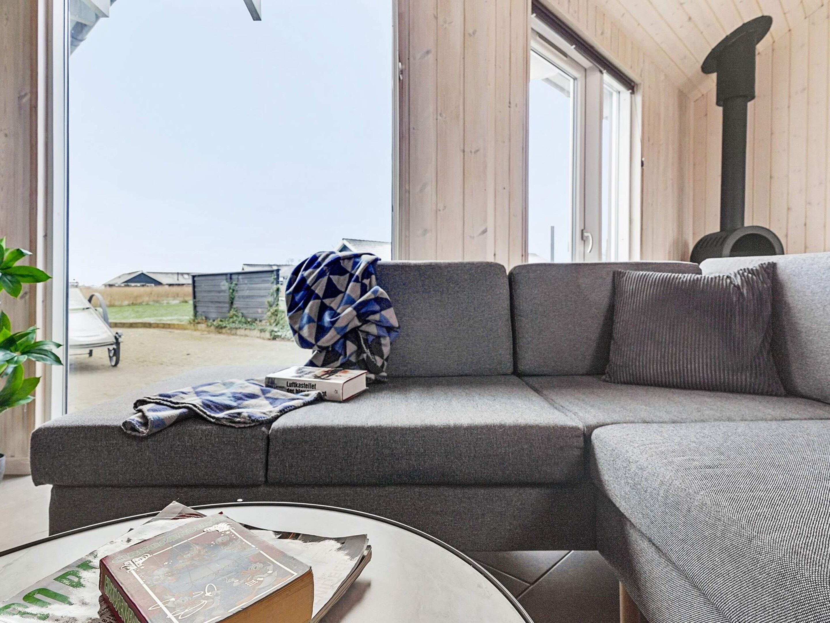 A modern living room with a grey sofa, a round coffee table, and a view of the outside.