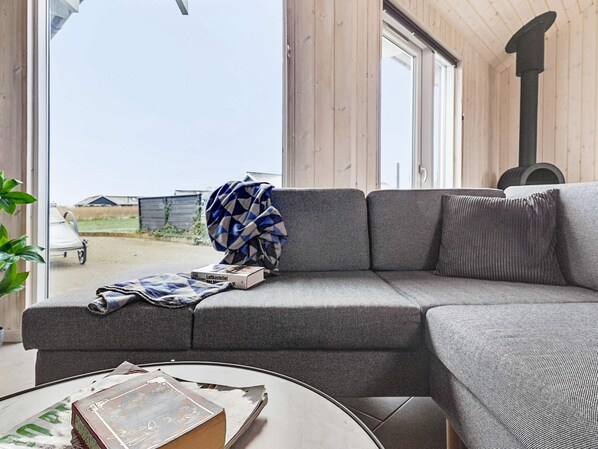 A modern living room with a grey sofa, a round coffee table, and a view of the outside.