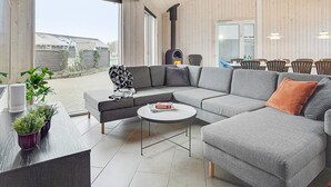 Een moderne woonkamer met een modulaire bank, een ronde salontafel, en een eethoek met stoelen en een tafel.