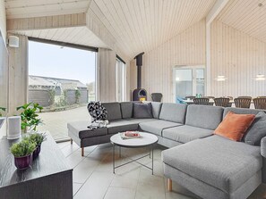 A modern living room with a sectional sofa, a round coffee table, and a dining area with chairs and a table. - 5 Star Holiday Home in Sydals (Sydals)