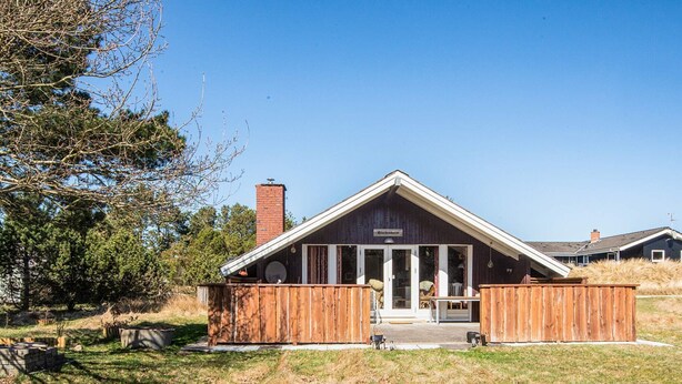 A rustic building with a sloped roof and a chimney, surrounded by a wooden fence and a grassy area. - 6 Person Holiday Home in Vejers Strand-by Traum (Vejers Strand)