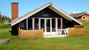 A small, single-story building with a sloped roof and a chimney. It has a covered patio with outdoor seating and a sign that reads "Storchennhaus". - 6 Person Holiday Home in Vejers Strand-by Traum (Vejers Strand)