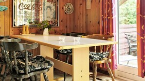 A wooden interior with a table and chairs, a vintage Coca-Cola poster, and a window with curtains. - 6 Person Holiday Home in Vejers Strand-by Traum (Vejers Strand)
