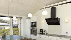 A modern kitchen with a large island, stainless steel appliances, and pendant lighting. - Seaside Bliss in Fyn - By Traum Ferienwohnungen (Faaborg)