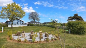 A residential area with a house, a tree, and a circular arrangement of tree stumps. - Seaside Bliss in Fyn - By Traum Ferienwohnungen (Faaborg)