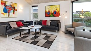 A modern living room with a sectional sofa, a coffee table, and artwork on the walls. - Seaside Bliss in Fyn - By Traum Ferienwohnungen (Faaborg)