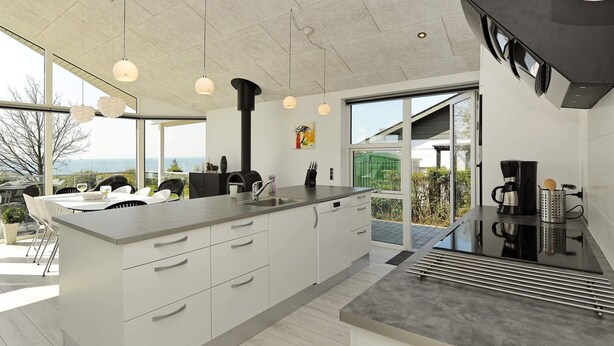 A modern kitchen with a large island, stainless steel appliances, and a view of the outdoors. - Seaside Bliss in Fyn - By Traum Ferienwohnungen (Faaborg)