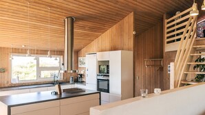 A modern kitchen with wooden walls, a central island, and a stainless steel range hood. - 4 Star Holiday Home in Hjorring (Hjørring)