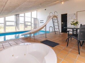 Une piscine avec un toboggan, un jacuzzi et une table avec des chaises.