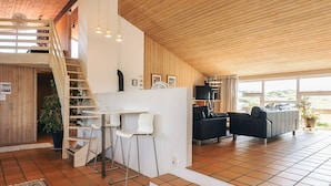 A spacious living area with a staircase leading to an upper level, a seating area with a sofa and chairs, and a television. - 4 Star Holiday Home in Hjorring (Hjørring)