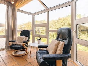 Une pièce avec deux fauteuils en cuir noir, une petite table et une plante en pot.