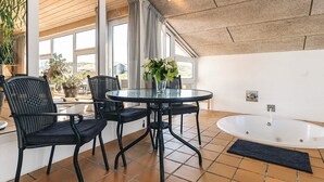 A modern bathroom with a glass-enclosed shower, a round glass table with chairs, and a large window providing natural light. - 4 Star Holiday Home in Hjorring (Hjørring)