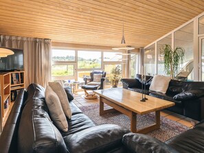 A modern living room with a leather sofa, a wooden coffee table, and a television on a stand. - 4 Star Holiday Home in Hjorring (Hjørring)