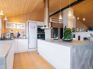 A modern kitchen with a large island, wooden ceiling, pendant lighting, and a refrigerator with magnets. - 4 Star Holiday Home in Hjorring (Hjørring)