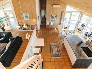 Un vaste espace de vie comprenant une cuisine moderne, un coin repas et un salon avec un canapé en cuir noir.