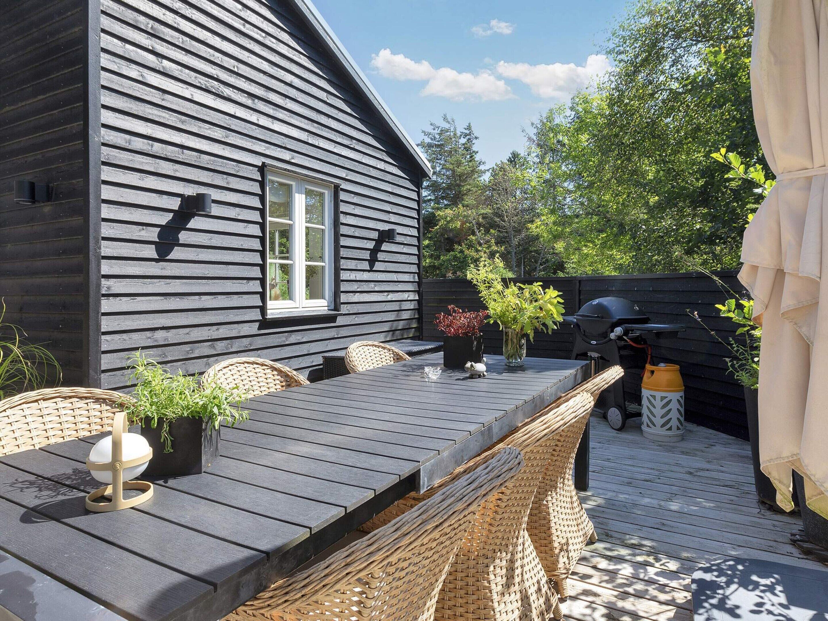 A deck with a table and chairs, a grill, and potted plants.