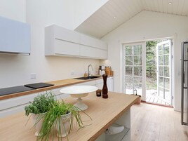 A modern kitchen with a wooden countertop, a white sink, and a potted plant.