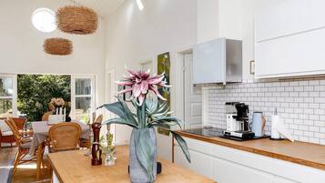 Una cocina moderna con armarios blancos, encimera de madera y un jarrón grande con flores.