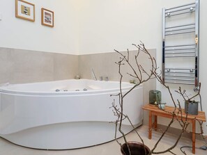 A modern bathroom with a freestanding bathtub, a wooden side table with a vase, and a towel rack. - 6 Person Holiday Home in Blokhus-by Traum (Blokhus)