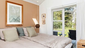 A bedroom with a large bed, a window with a view of greenery, and a framed artwork on the wall. - 6 Person Holiday Home in Blokhus-by Traum (Blokhus)