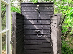 A wooden outdoor shower enclosure with a hose and a handheld showerhead. - 6 Person Holiday Home in Blokhus-by Traum (Blokhus)