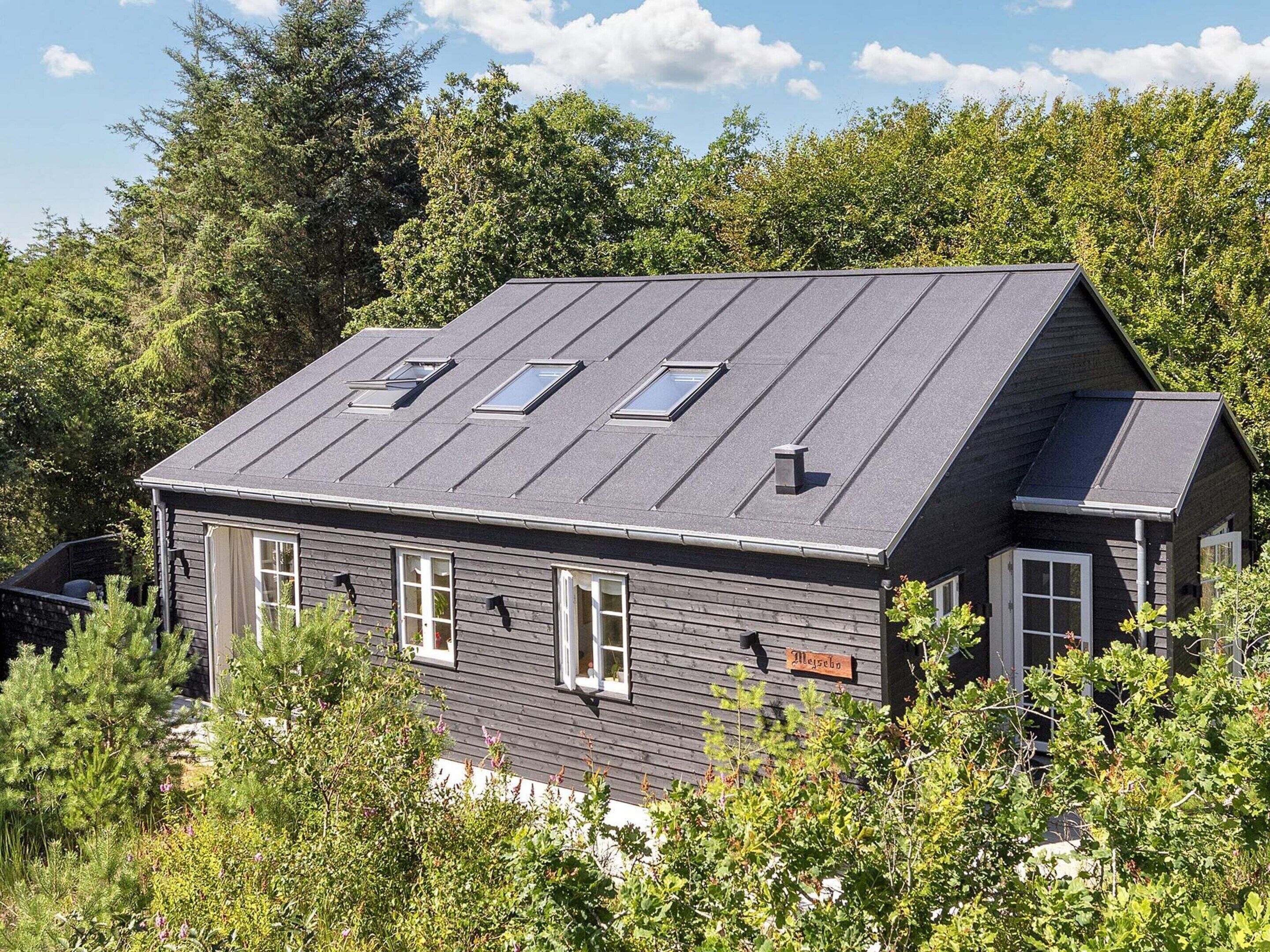 Une maison à deux étages, dotée d’un toit en pente, de nombreuses fenêtres et d’une cheminée bien visible.