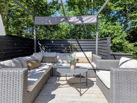 An outdoor patio with wicker furniture, a round table, and a potted plant.