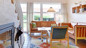 Un salon chaleureux avec une cheminée, un ensemble de canapés, une table basse et un tapis à motifs.