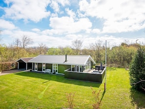 A modern house with a large patio area, a covered outdoor seating space, and a well-maintained lawn.