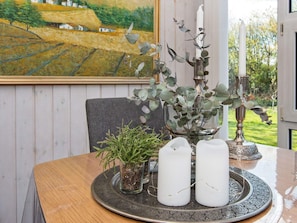 A dining table with a glass vase, a potted plant, and two candles.