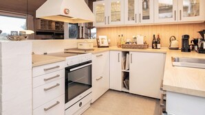 Une cuisine moderne avec des meubles blancs, un four encastré et une grande hotte aspirante blanche.