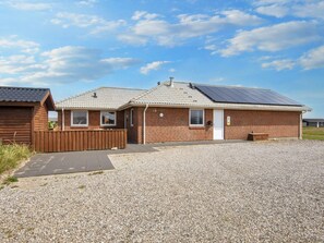 A single-story brick building with a gravel driveway and a wooden fence. - 4 Star Holiday Home in Harboore (Harboore)