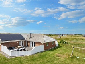 A house with a solar panel roof, a patio with outdoor furniture, and a grassy yard. - 4 Star Holiday Home in Harboore (Harboore)