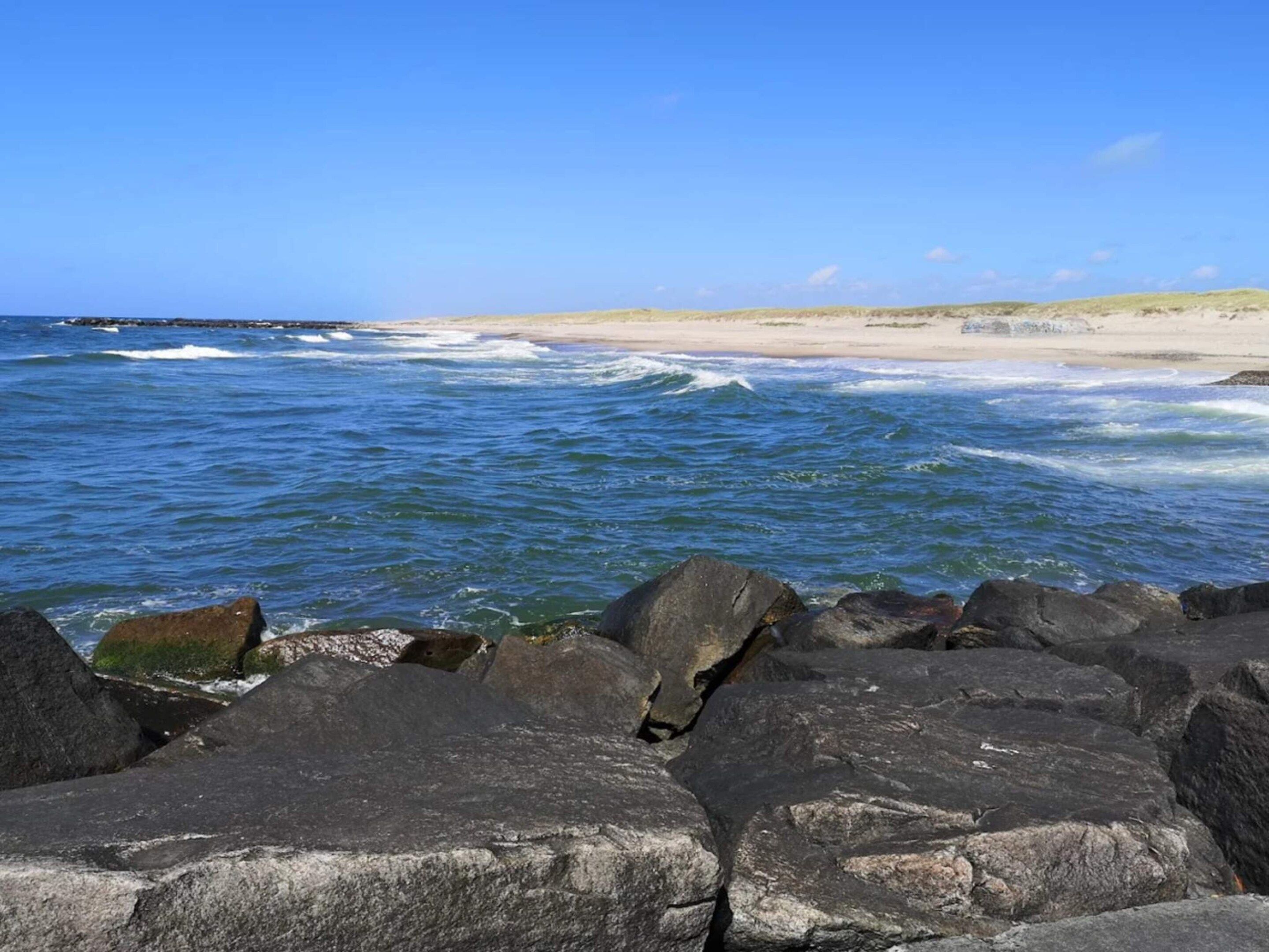 Una costa rocosa con olas rompiendo en la playa.