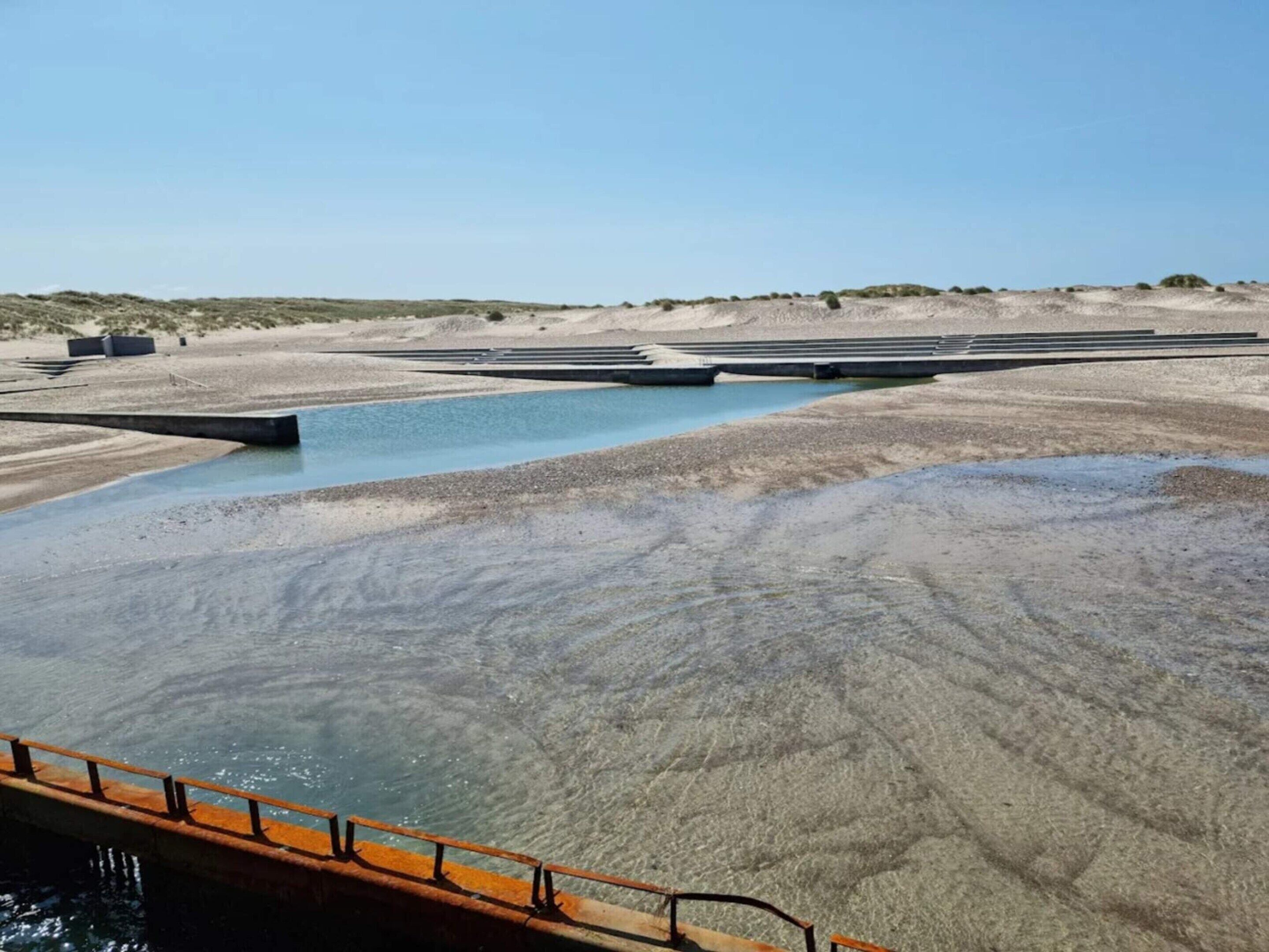 Un paisaje seco y extenso con un cuerpo de agua y un puente.