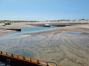 Un paysage aride et sec, avec une étendue d’eau importante et un pont.