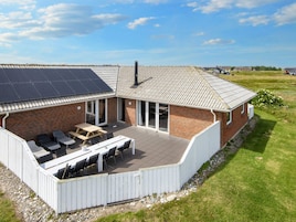 Una casa con porche cubierto, fachada de ladrillo y panel solar en el techo.